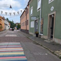 Stadsgata med hus i glada färger och målade trasmattor på asfalten.