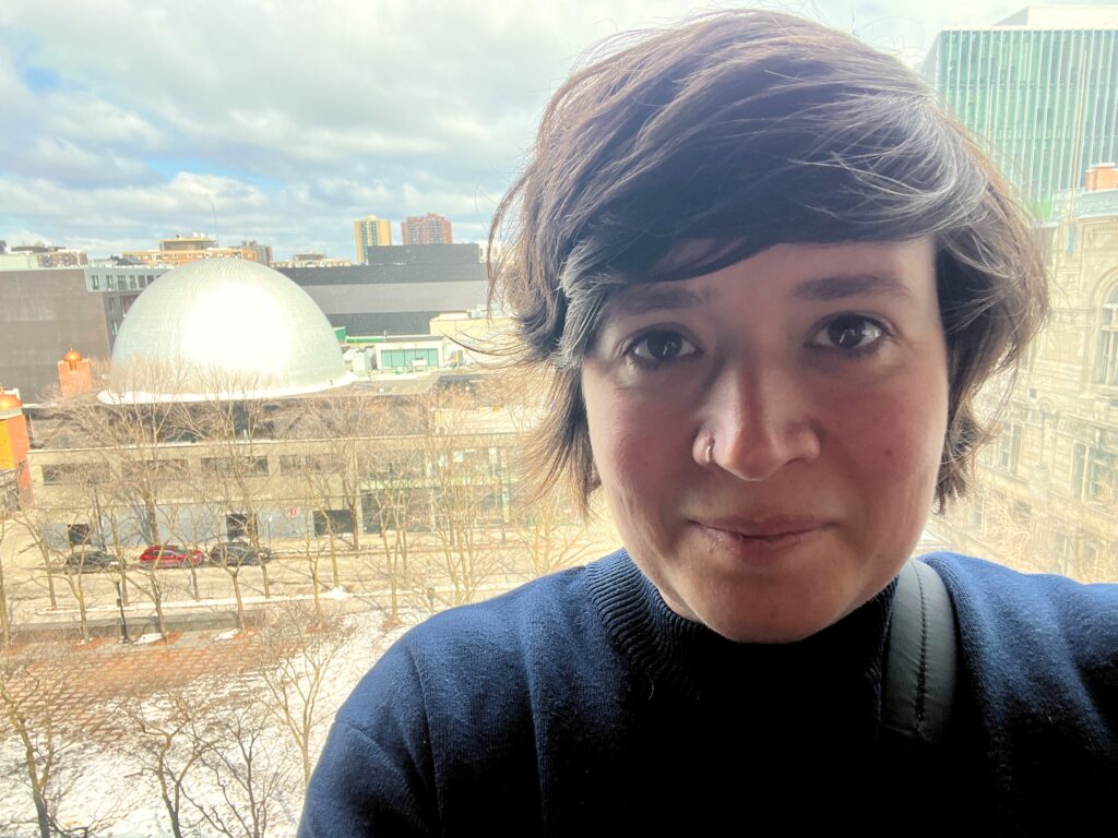 Kvinna vid fönster med utsikt över kupolbyggnad