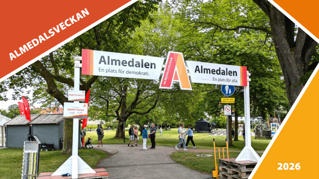 Vy över Almedalsparken med stora gröna träd i bakgrunden och några bodar för besökare längs gångstigar.