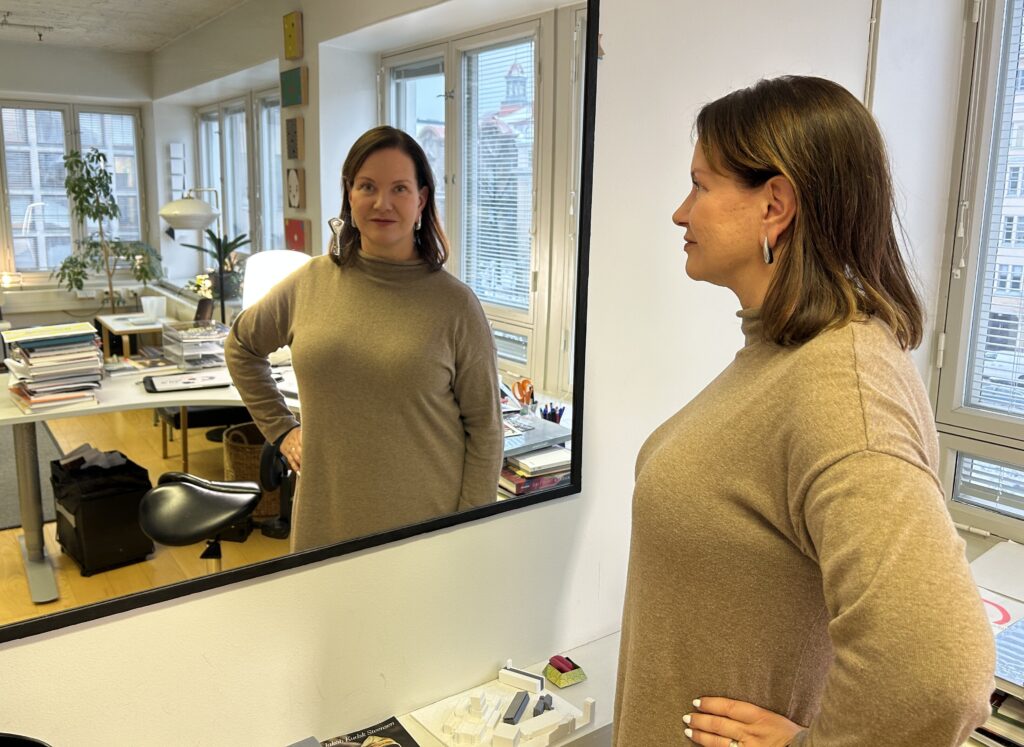 Kvinna tittar in i kameran genom en spegel