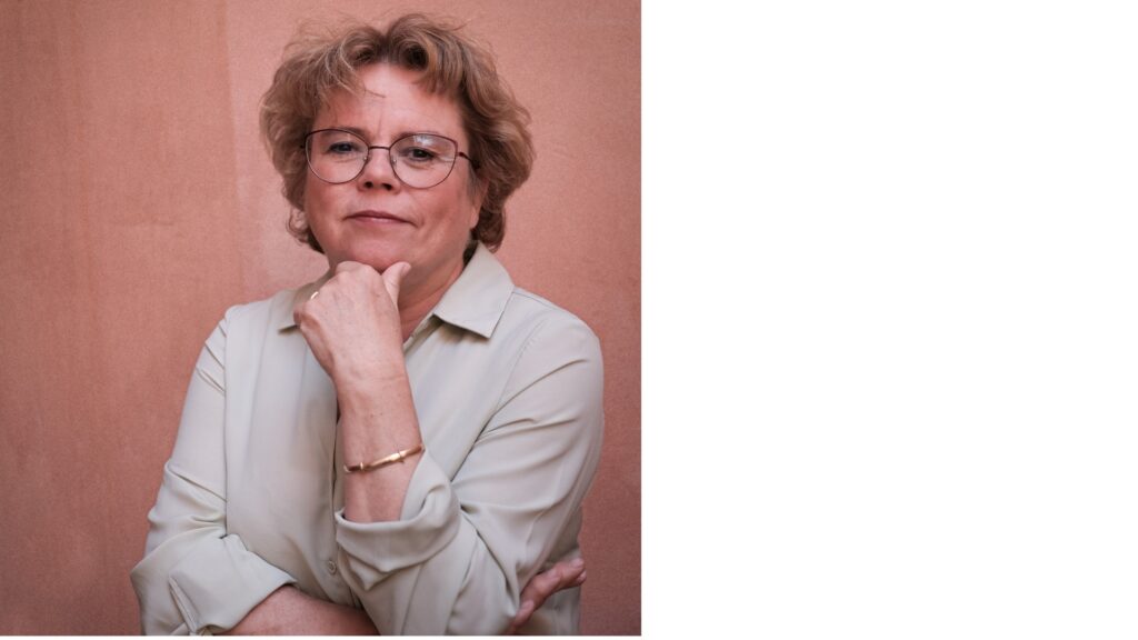 Porträttbild föreställande kvinna som vilar hakan i ena handen, rosa bakgrund.
