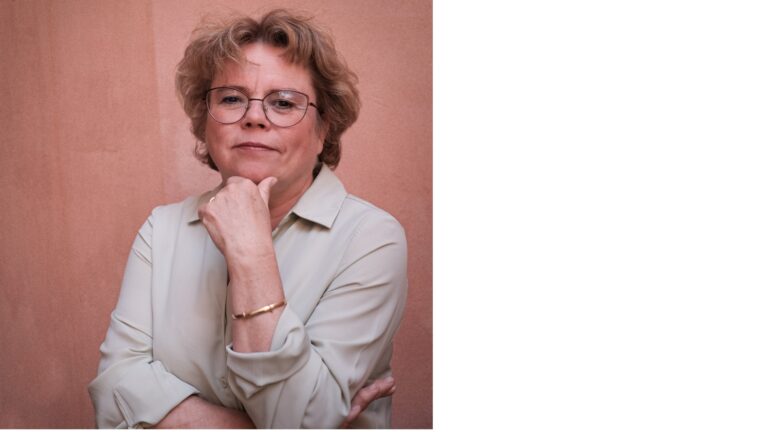 Porträttbild föreställande kvinna som vilar hakan i ena handen, rosa bakgrund.