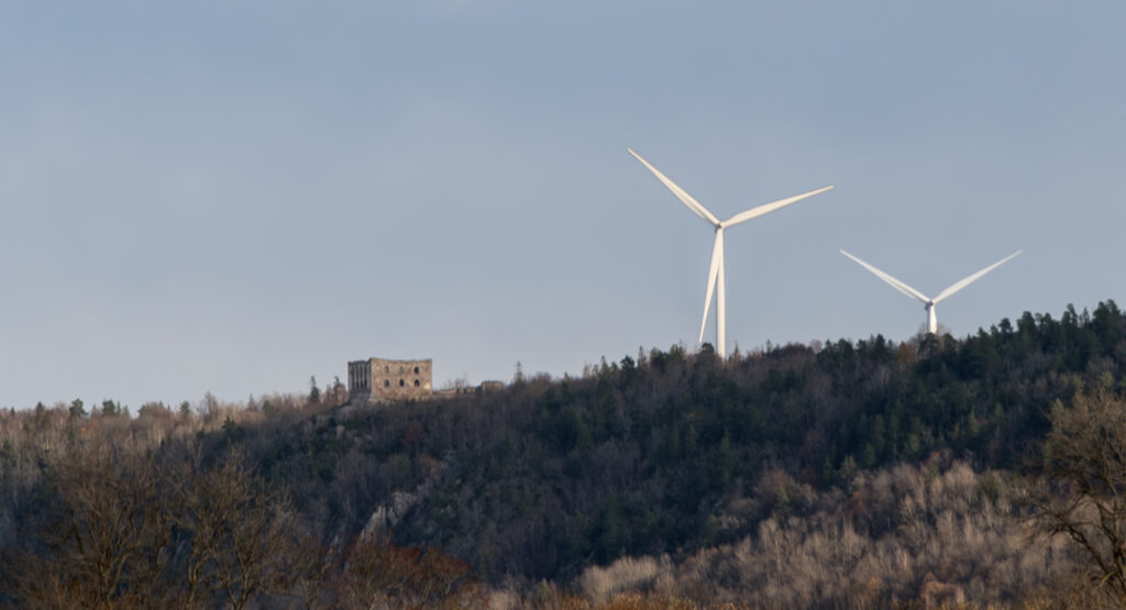 Fornlämningen Brahehus utanför Gränna, i förgrunden ett vitt vindkraftverk.