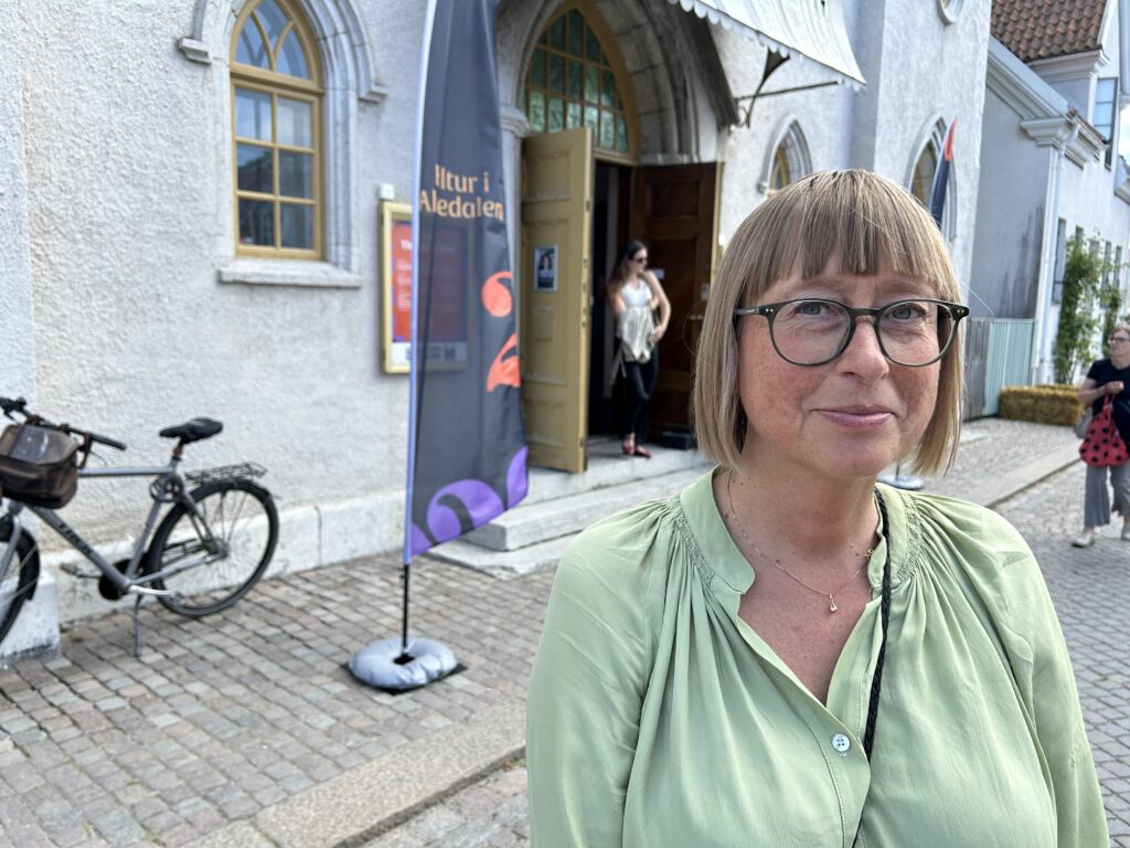 Kvinna framför entrédörr och vimpel