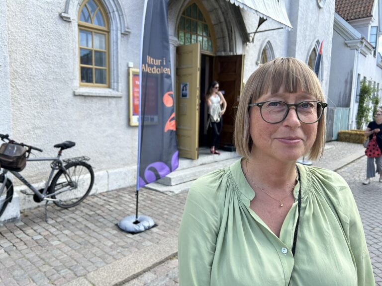 Kvinna framför entrédörr och vimpel