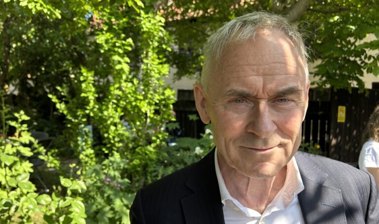 Porträtt på man framför grön buske