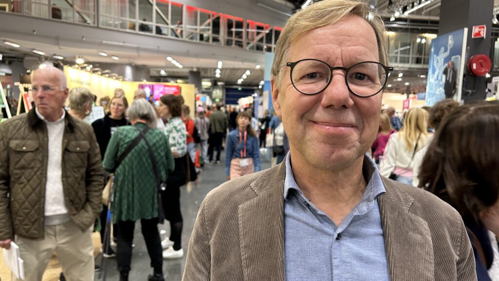 Porträttfoto på man med glasögon i en mässhall.