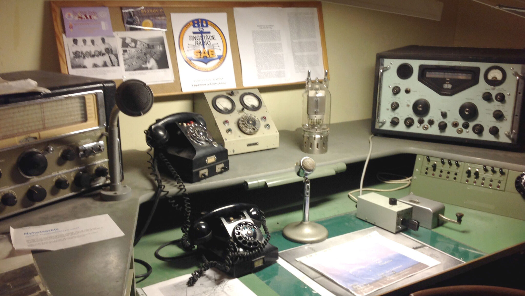 Nere i fästningen står ett skrivbord med flera gamla telefoner och radioapparater.