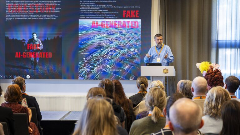 En man står vid en pulpet inför publik i en föreläsningssal.
